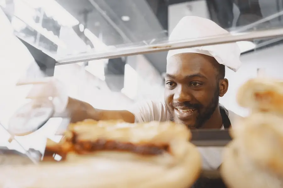 A baker arranging fresh bread in a display case — a stock photograph illustrating the scenario, not a client.