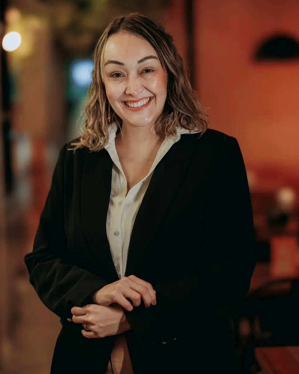 Odette Fontenot in a dark blazer, smiling, in a warmly lit room — a stock portrait photograph.