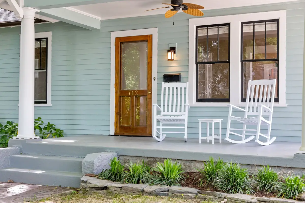A front porch with rocking chairs and a painted wooden door.